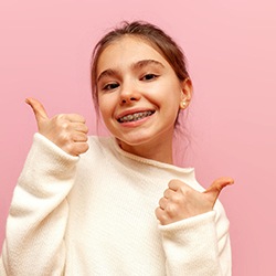 A girl with braces giving a thumbs up