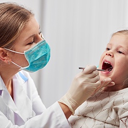 A dentist examining a little girl’s mouth