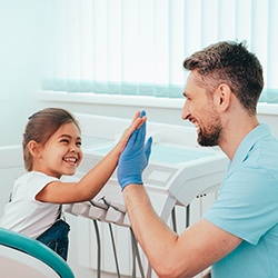 A young girl high-fiving her pediatric dentist