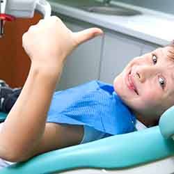 Little boy in dental chair giving a thumbs up