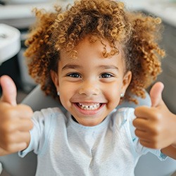 Young patient giving two thumbs up during a dental visit